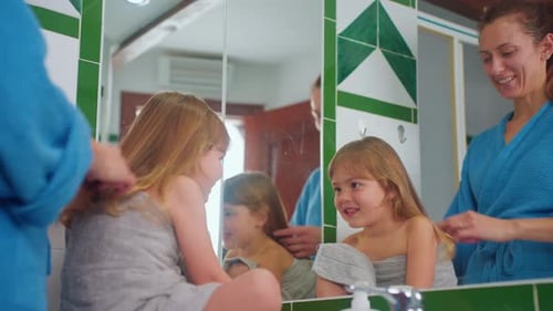 Woman Brushing Child's Hair in Bathroom Mirror