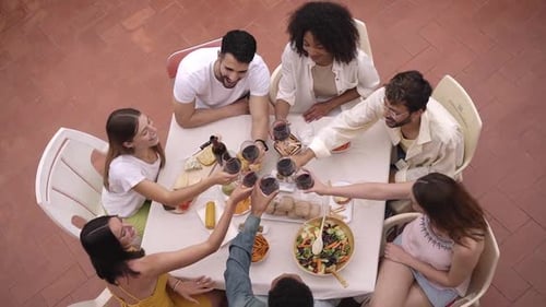 Top View of Happy Group of Friends Toasting with Red Wine Outside in a Terrace Celebrating