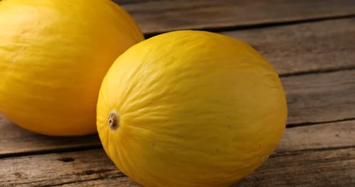 Ganze reife Melonen auf Holztisch, Nahaufnahme. Kamera bewegt sich nach links