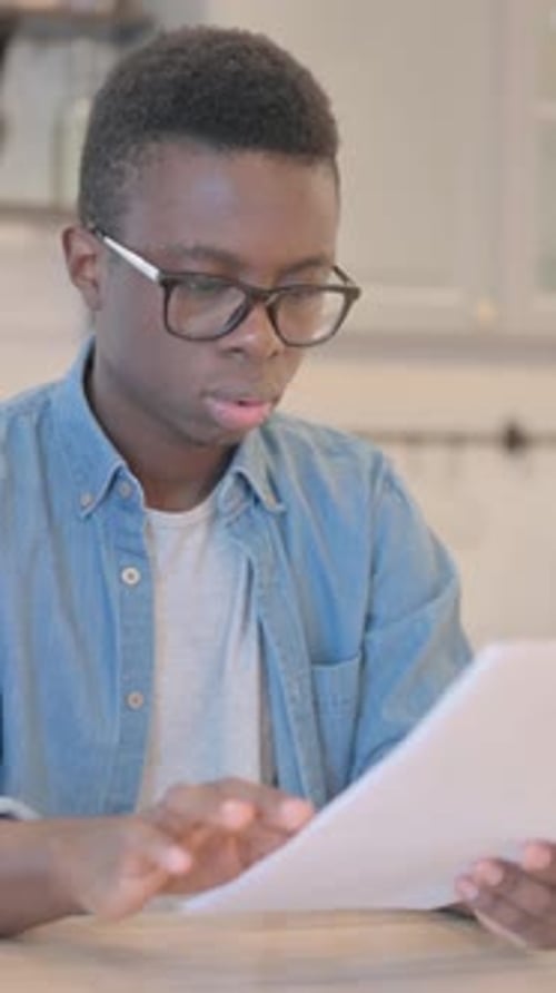 Excited Man Reads Document at Table Indoors