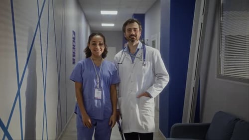 Male and Female Doctors Stand Sidebyside Smiling in Corridor