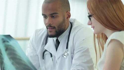 Smiling Doctor Talking to Patient While Sitting at a Table in the Hospital