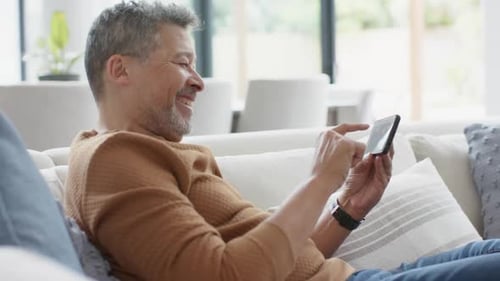 Man Relaxing on Couch Using Cell Phone