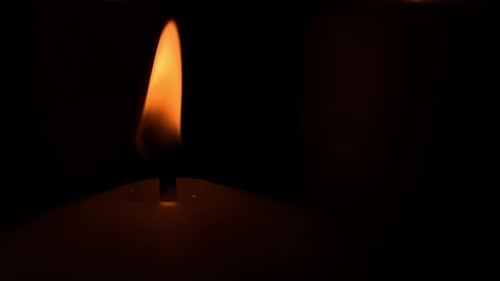 Nahaufnahme einer einzelnen orangefarbenen Flamme auf schwarzem Hintergrund, langsame Feuerbewegung einer brennenden Kerze, statisches Licht