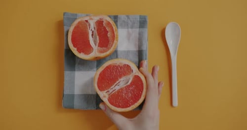 Fresh Grapefruit halves on Orange Surface with Spoon