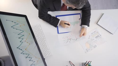 Adult Checks Charts in Office from Above