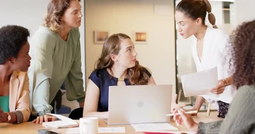 Diverse businesswomen having meeting and using laptop at office, in slow motion