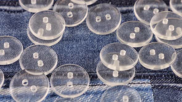 Clear Buttons Falling onto Blue Denim Background, Slow Motion Stock ...