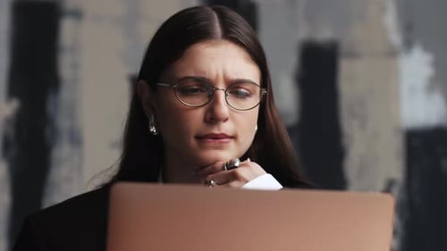 Thoughtful Young Woman Working on Laptop