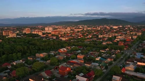 Stadt mit vielen Häusern und Bergen im Hintergrund in der Abenddämmerung mit blauem Himmel und Wolken