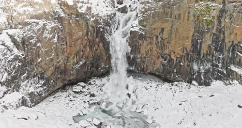 Aerial Shot Of Snowy Cliffs And Cascading Falls