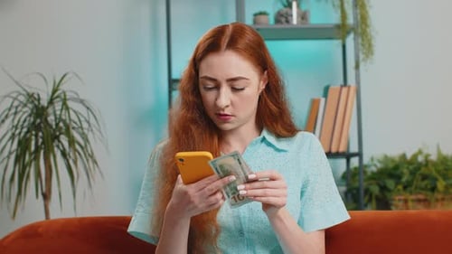 Young Woman Using Phone While Holding Cash