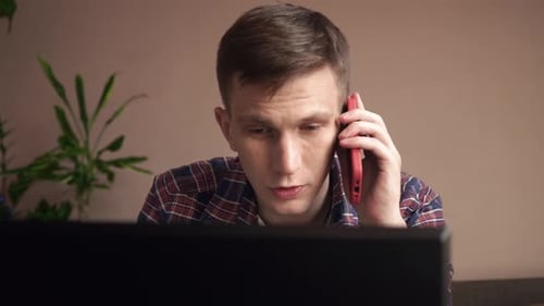 young man talking on a mobile phone at work. cozy home environment. close-up.