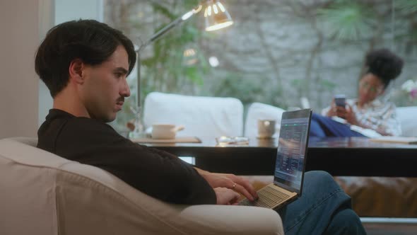 Programmer Working on Laptop from Home, Wife Sitting in Background ...