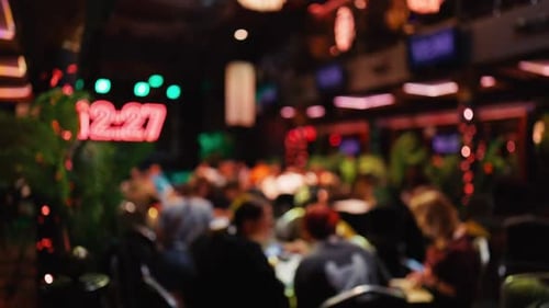 A Blurry Background Showcasing a Busy Restaurant Filled with Colorful Neon Lights and Lush Plants