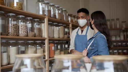 Male Owner of Zero Waste Shop Advising Customer. Coronavirus Concept