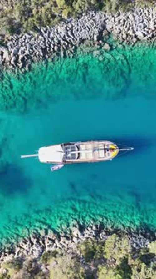 Aerial shot of boat turquoise water in sunny cove
