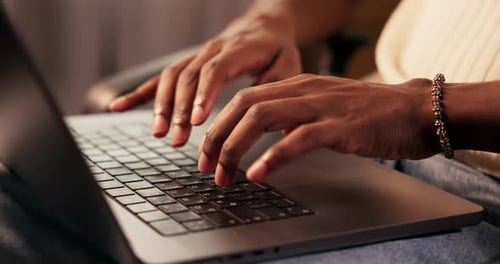 Nahaufnahme der Hände eines Afroamerikaners, der während der Arbeit auf der Tastatur eines Laptops mit den Finger tippt