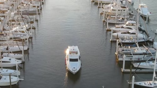 Yacht Cruising By The Calm Waters Between Moored Boats In The Marina. - aerial