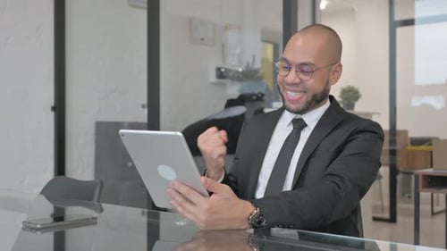 Happy Businessman Celebrating Success Using Tablet in Office