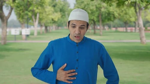 Sick Muslim man suffering from stomach pain in park