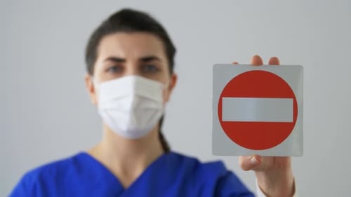 Female Medical Professional with Mask Holding Sign