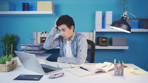 Young student studying under stress and looking at laptop with nervous eyes.