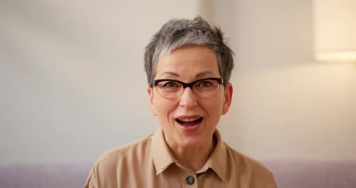 Mature Woman Smiling and Waving in Home Setting