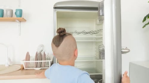 Boy Opens Empty Refrigerator in Clean Kitchen