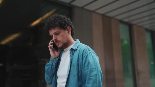 Close-up, of man talking on mobile phone and walking down the street