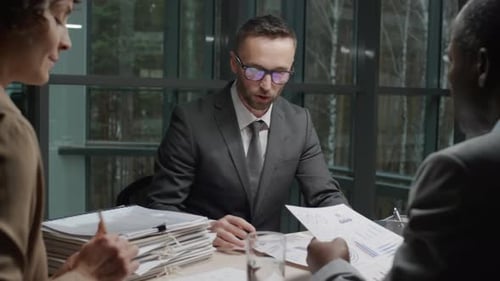 Business People Discuss Charts and Graphs in Office Meeting