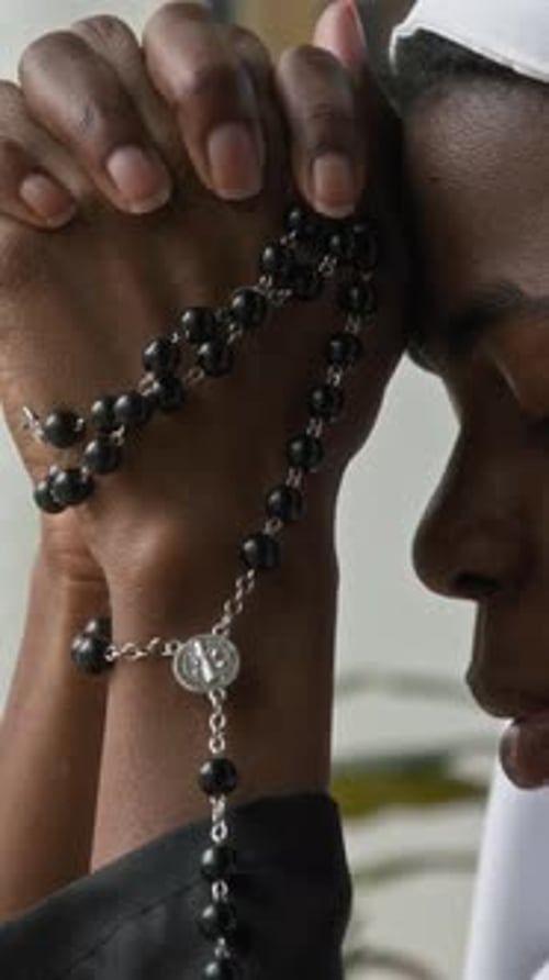 Close Up of Person Praying with Rosary Beads