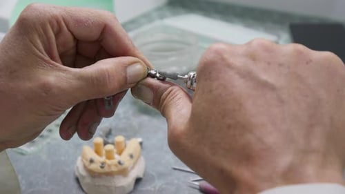 Dental Technician Refining Metal Dental Bridge