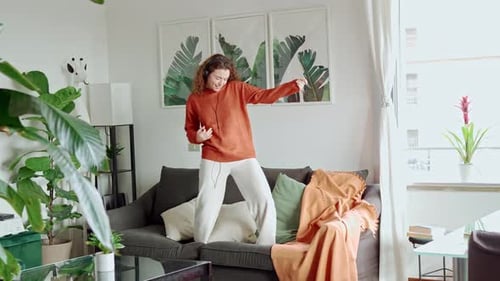 Young Woman Dancing Joyfully on Sofa at Home