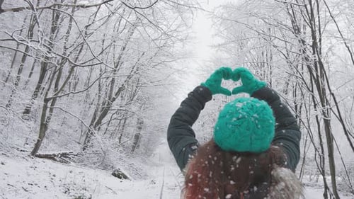 In a Serene Snowy Forest a Woman Creates a Heart with Her Hands Symbolizing Beauty Peace and Love in