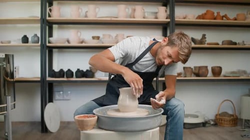 Potter Shaping Vase on Pottery Wheel in Studio