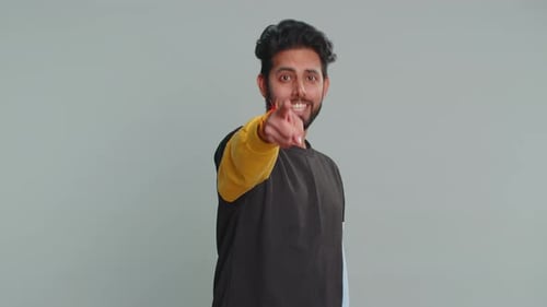 Indischer Mann lächelt aufgeregt und zeigt in die Kamera und wählt den glücklichen Gewinner aus und sagt: Hey du