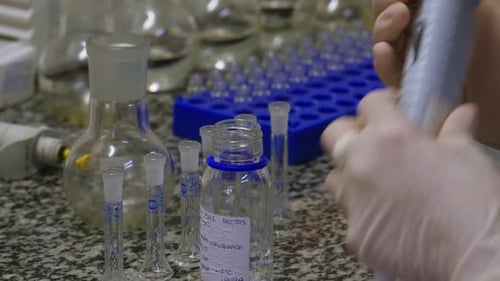 Lab Technician Using Pipette With Glassware in Laboratory