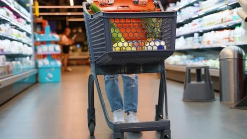 Uma compradora empurra com confiança um carrinho cheio de mantimentos frescos no supermercado