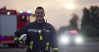 Fireman Smiling in Front of Fire Truck at Sunset