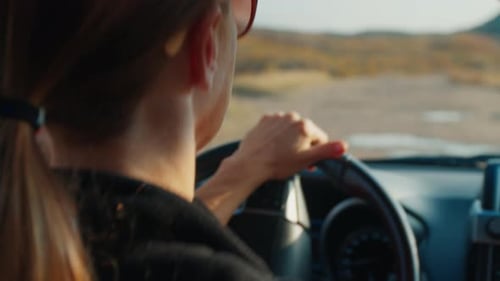 Young Woman Steers the Big 4X4 Car on a Bumpy Unpaved Road