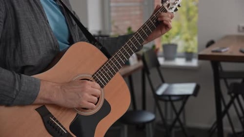 Person Playing Acoustic Guitar Indoors Close Up