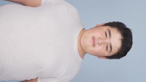 Vertical Video of Boy looking at camera with dull expression.