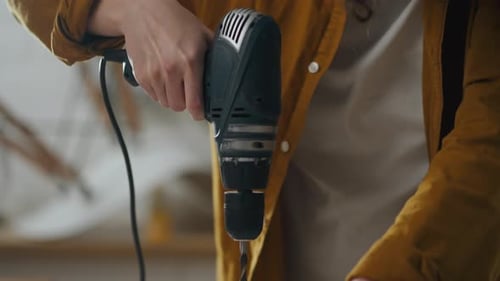 Man Uses Power Drill on Wood in Workshop