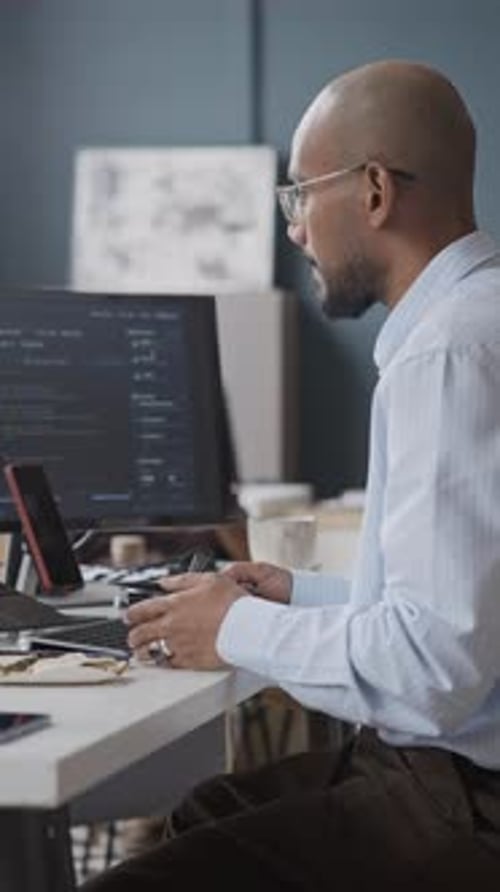 Focused Man Using Game Controller While Sitting at Desk and Snacking