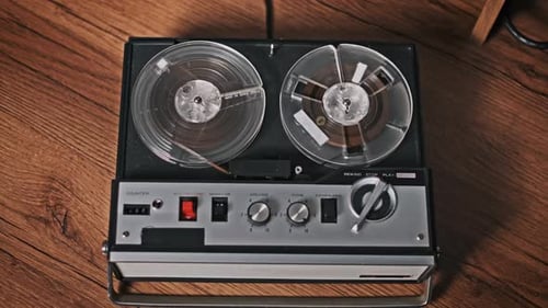 Vintage Reel-to-Reel Tape Recorder Spinning on Wooden Surface