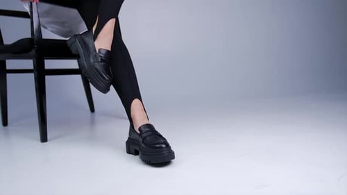 Woman modeling black platform loafers in studio