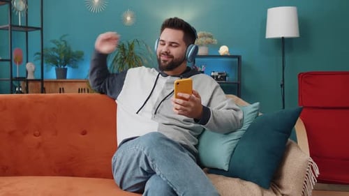 Man Listens to Music on Couch With Headphones