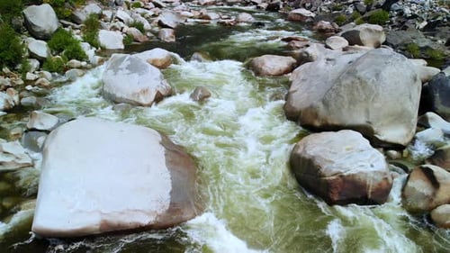 Slow Aerial fly over a river with strong rapids at 24 frames per second.