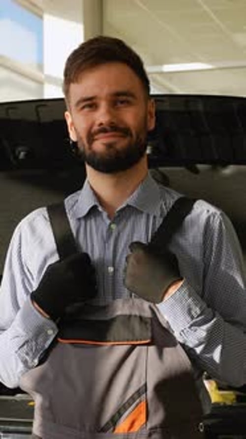 Mecânico de automóveis sorridente em frente ao capô aberto